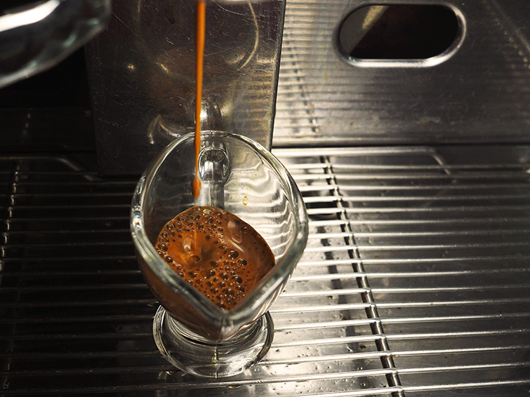 Zdjęcie kawy wlewającej się do filiżanki z ekspresu kolbowego